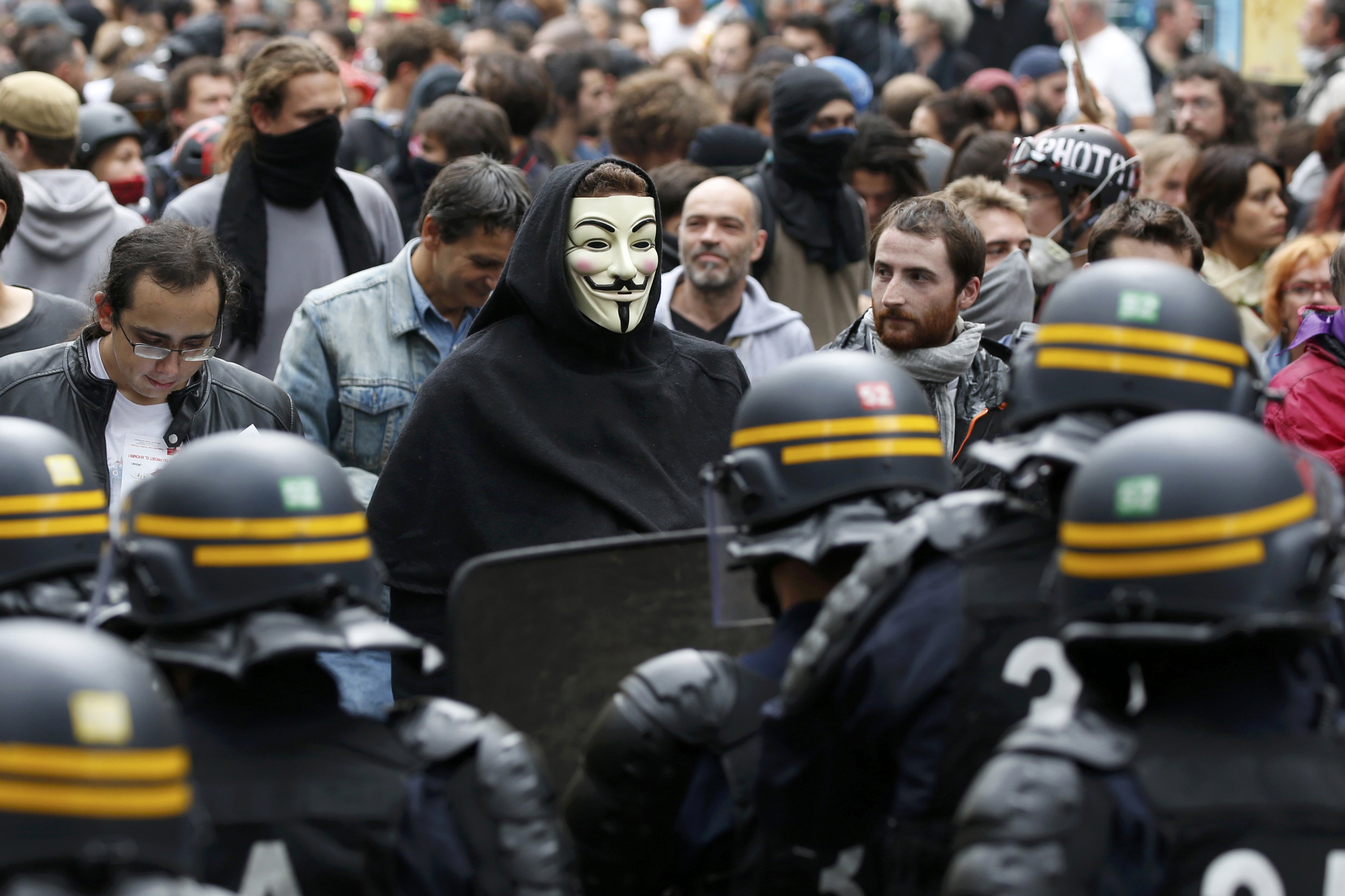 A protester, wearing a Guy Fawkes mask, walks past French riot police as French labour union members march march in Paris, France, to demonstrate against the new French labour law, September 15, 2016. REUTERS/Charles Platiau